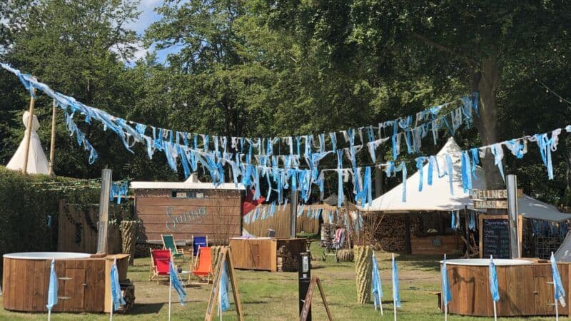 Spieriewierie wellness setup at a festival with blue ribbons, sauna huts and hot tubs