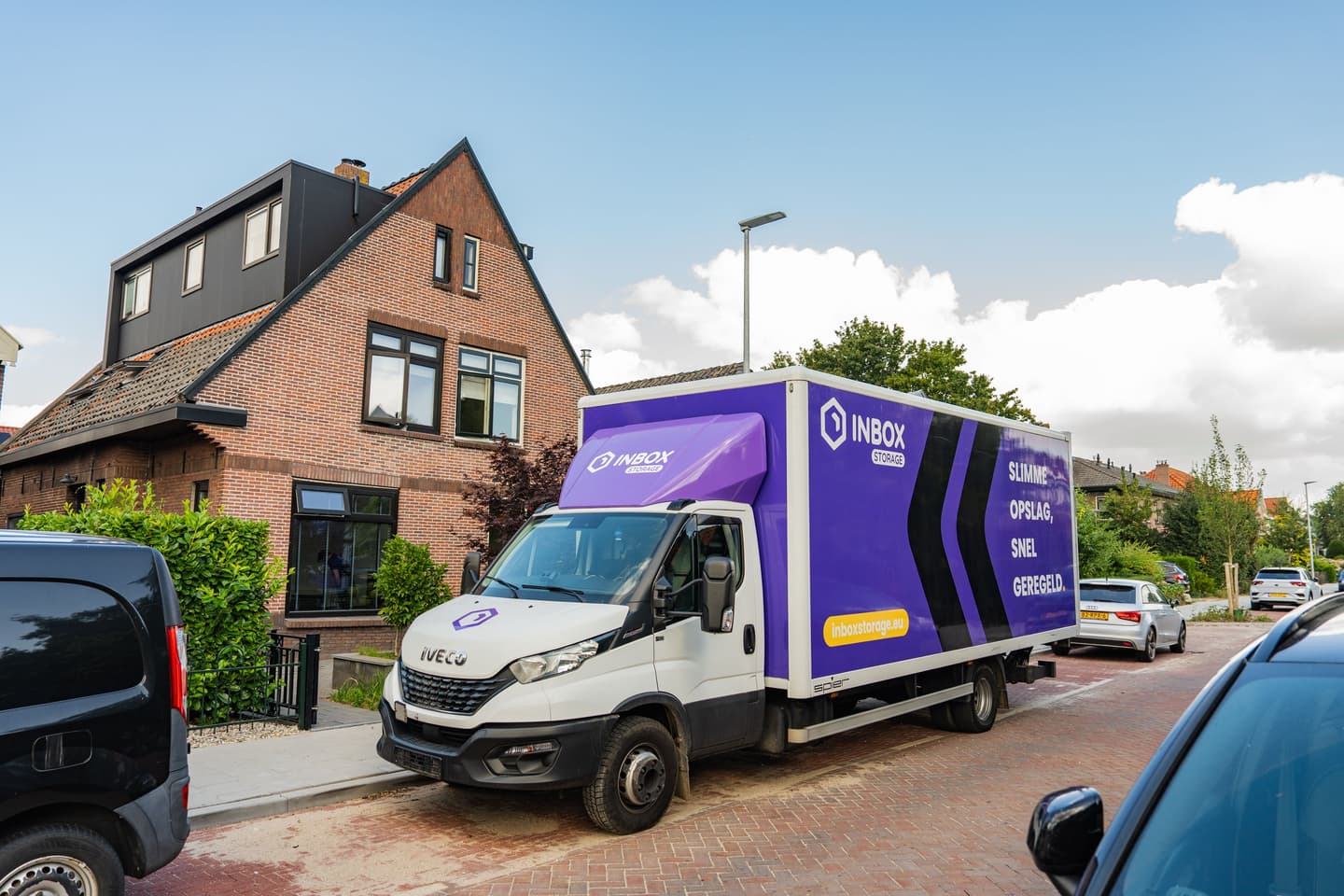 Vrolijk stel met verhuisdozen in een lege kamer — ruimte maken begint hier met Inbox Storage