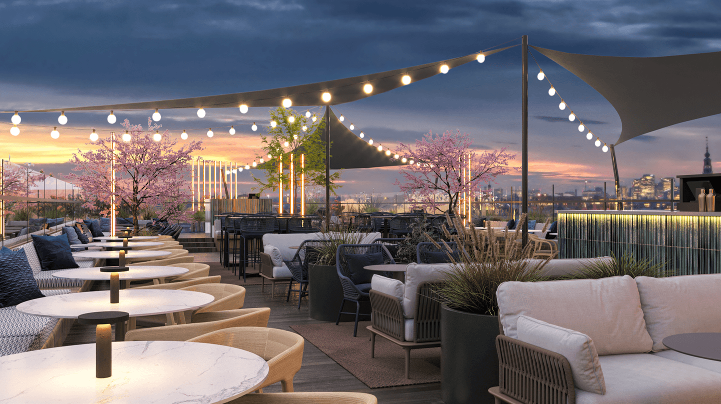 Rooftop terrace of DoubleTree by Hilton Amsterdam Centraal at sunset, with string lights, cherry blossom trees and lounge furniture